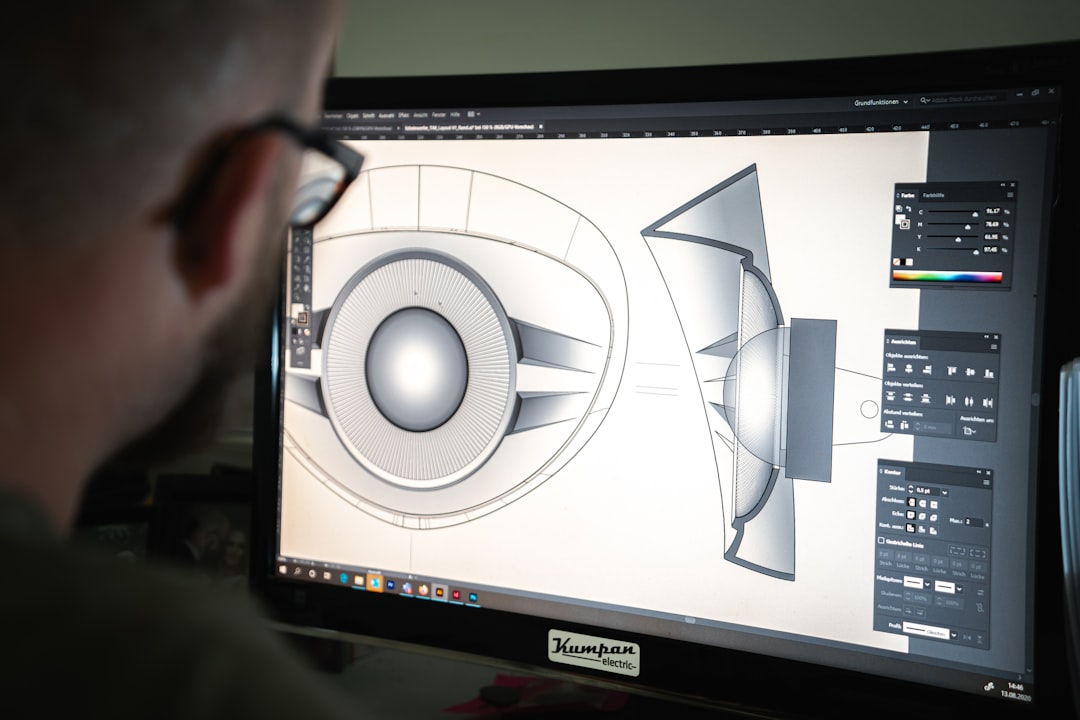 Designer examining a 3D CAD drawing of a loudspeaker on a computer monitor
