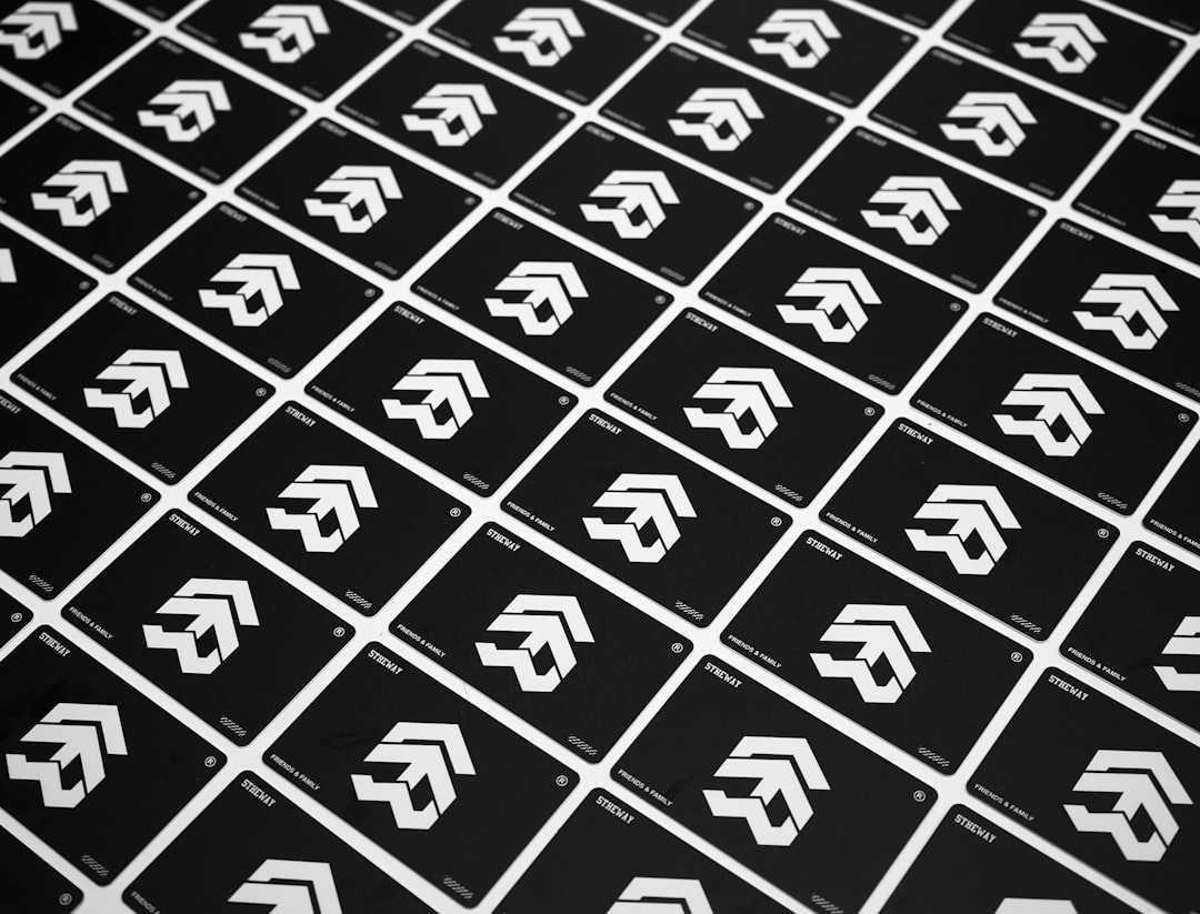 Pattern of repeated black business cards with a white angular logo.
