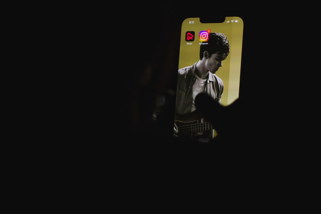 Phone held in a dark setting displaying a musician image on the screen, with two app icons at the top.