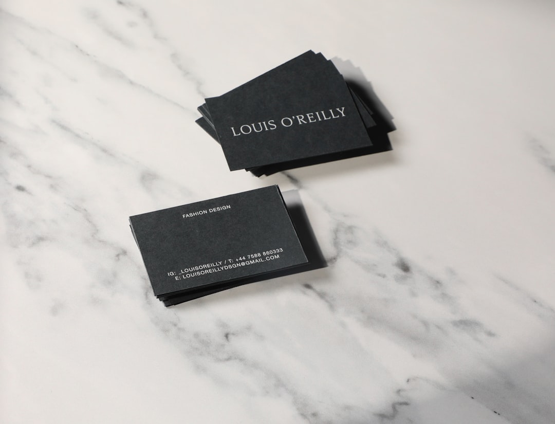 Stack of dark gray business cards on a marble surface; front card shows 'LOUIS O'REILLY'.