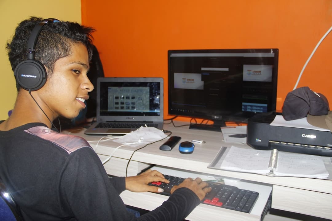 a young man sitting at a desk with headphones on code editor visual studio code student working - AI Bud