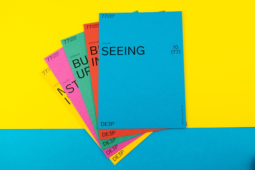 Stack of bright colored booklets fanned out with the blue cover reading SEEING on a yellow and blue background.