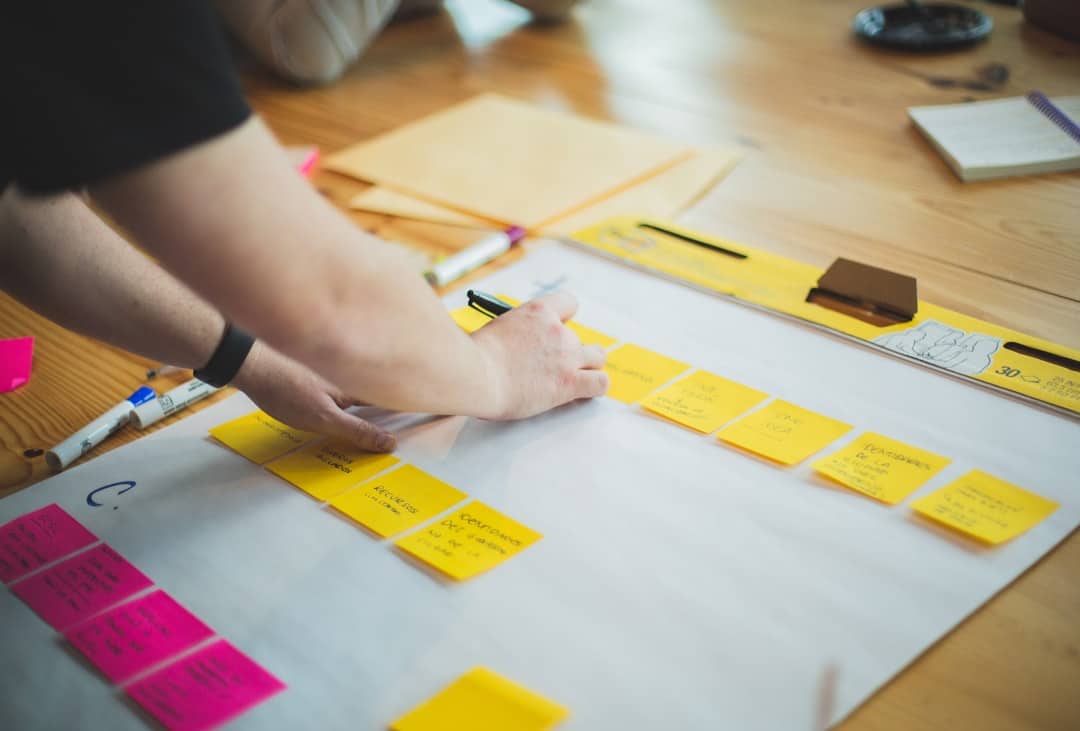 person writing on white paper support team pricing plans user interface - AI Bud