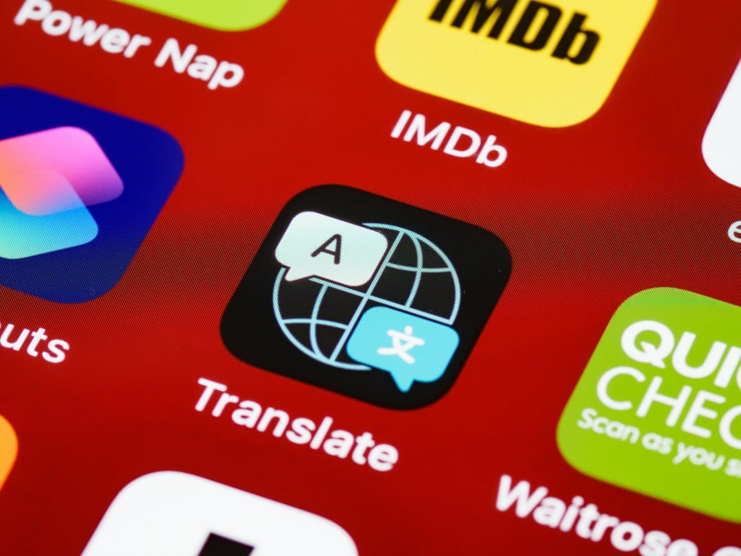 Translate app icon: globe with a speech bubble and an 'A' tile on a black rounded square, set on a red app grid background