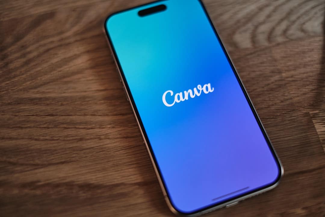 Smartphone on a wooden surface displaying the Canva logo with a blue-to-purple gradient screen.