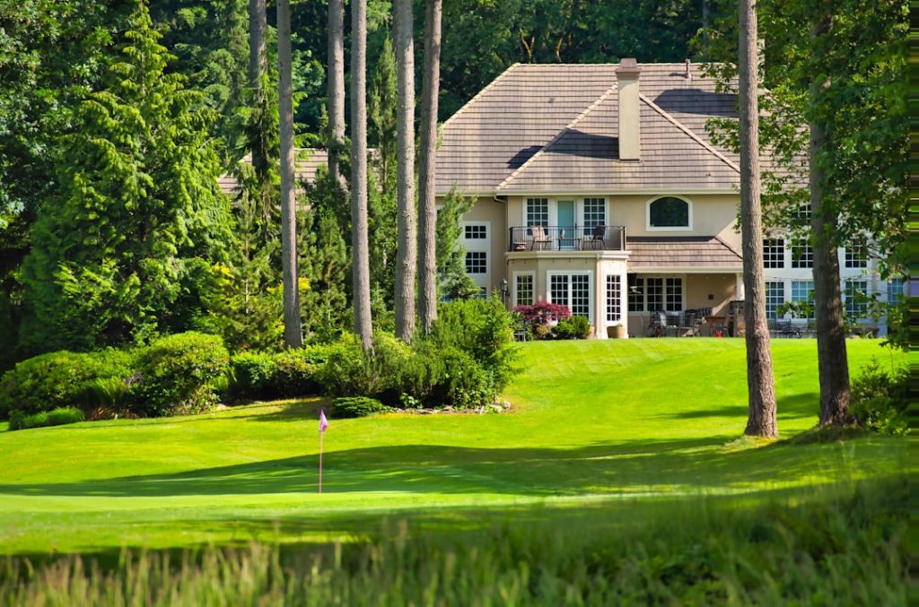 a golf course with a house in the background real estate listings property management commercial properties - AI Bud