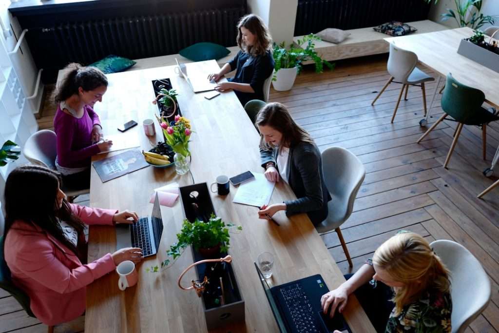 a group of people sitting around a wooden table startup team productivity lead success - AI Bud