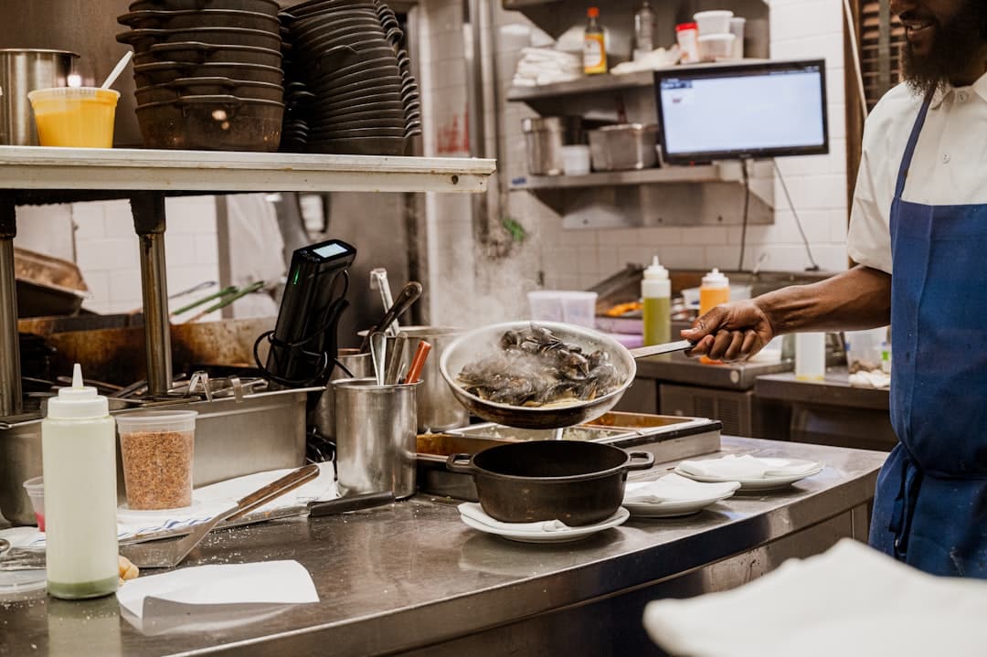 a man standing in a kitchen preparing food restaurant technology staff using pos kitchen order screen - AI Bud