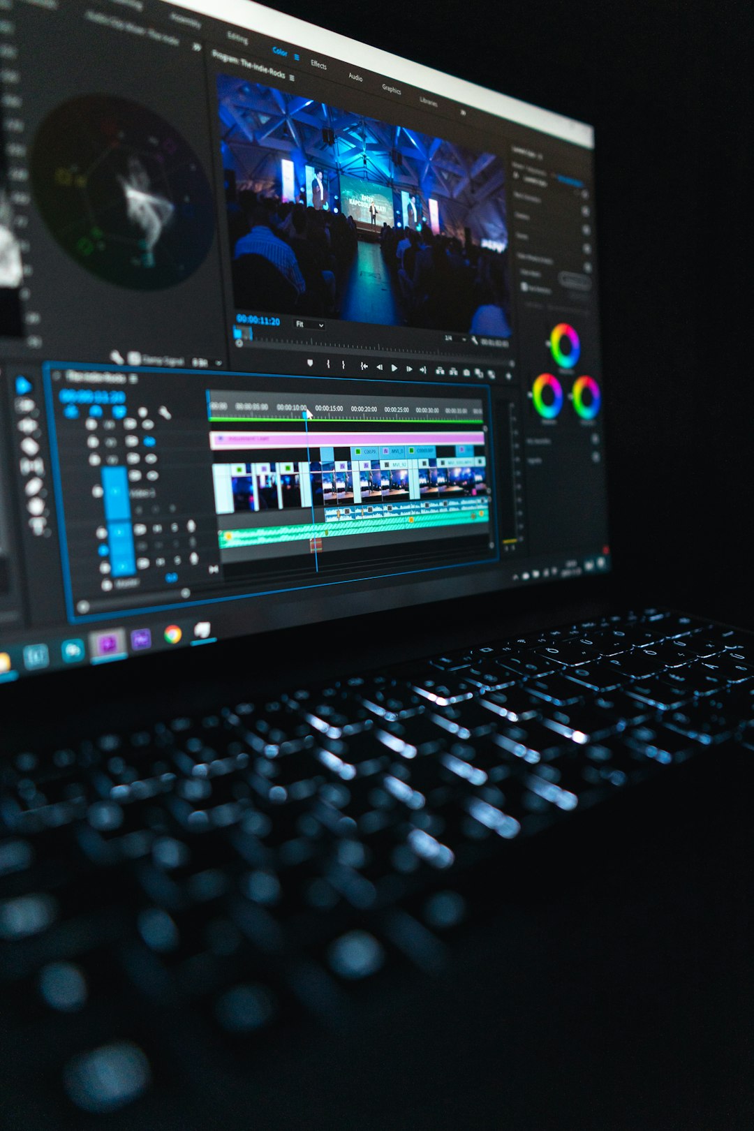 Monitor displaying video editing software with timeline and preview of a stage performance that’s being edited at a desk.