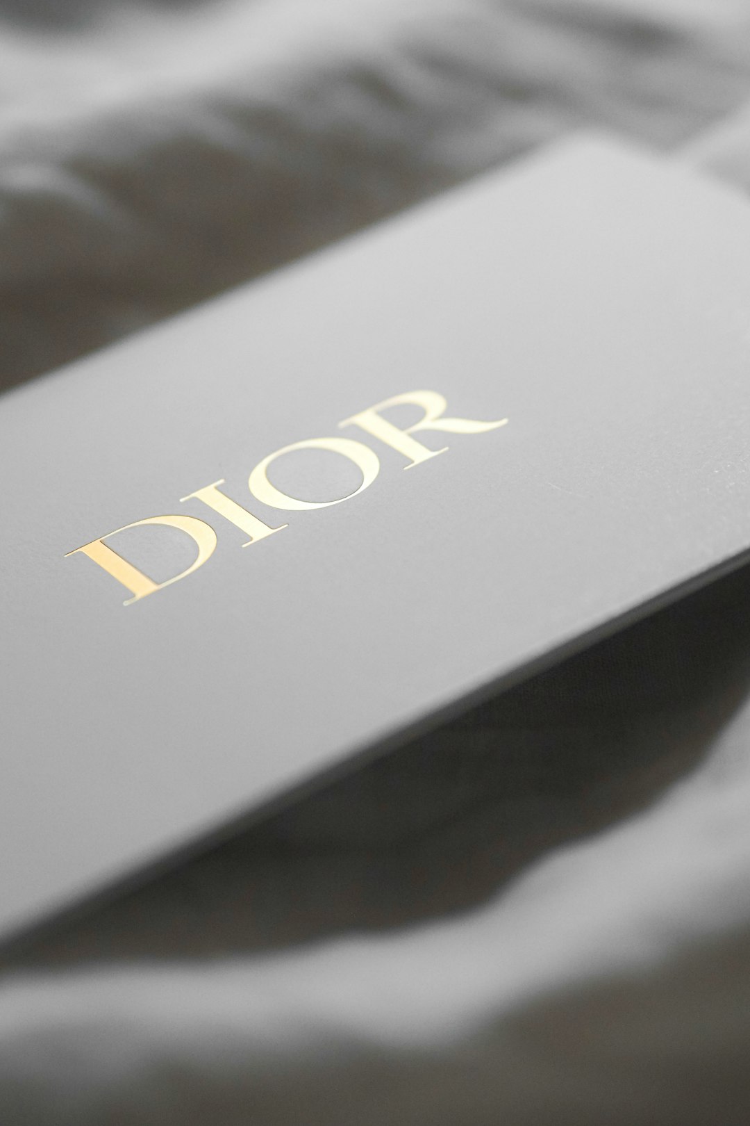 Gold DIOR logo on a gray box surface, close-up detail of branding