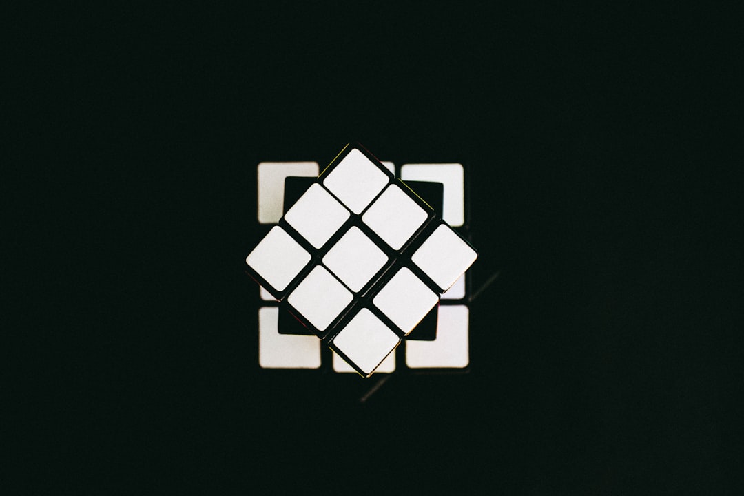 Close-up of a white Rubik's cube rotated on a dark background, showing several white facelets.