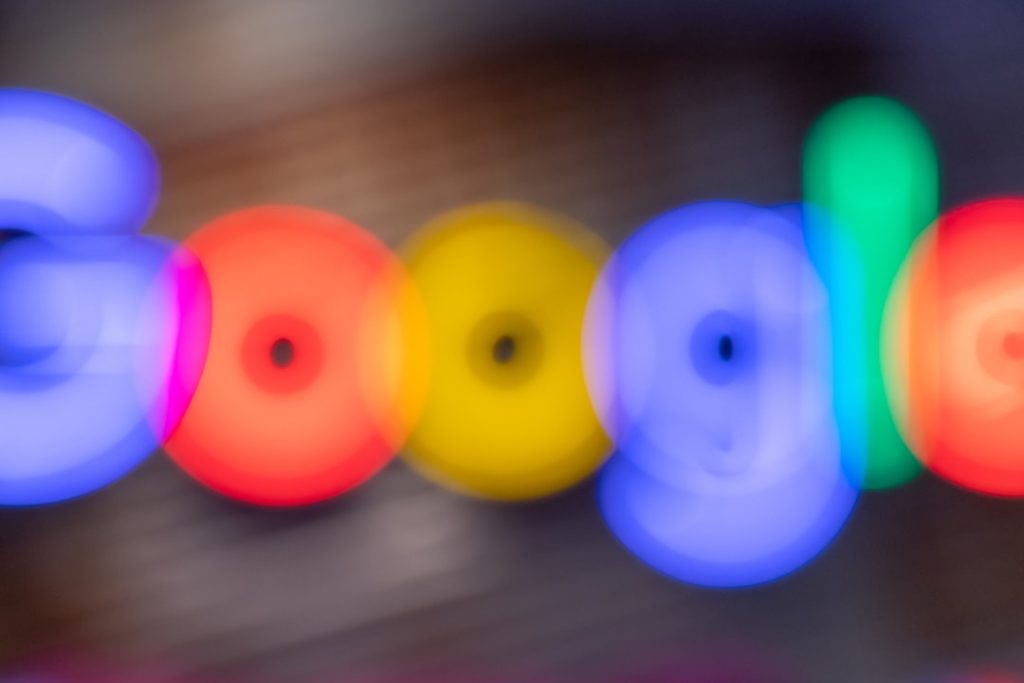 Blurred multicolor Google logo letters formed by glowing circles.