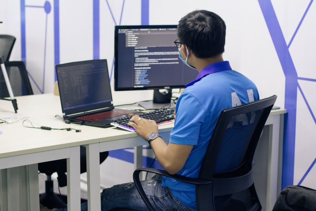 boy in blue t-shirt sitting on black office rolling chair in front of computer job queue task processing distributed system - AI Bud