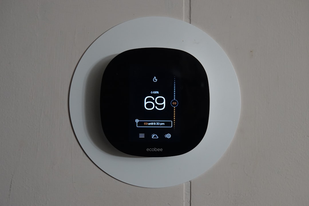 Smart thermostat on a wall plate showing 69°F current temperature and status icons on the screen (Ecobee).