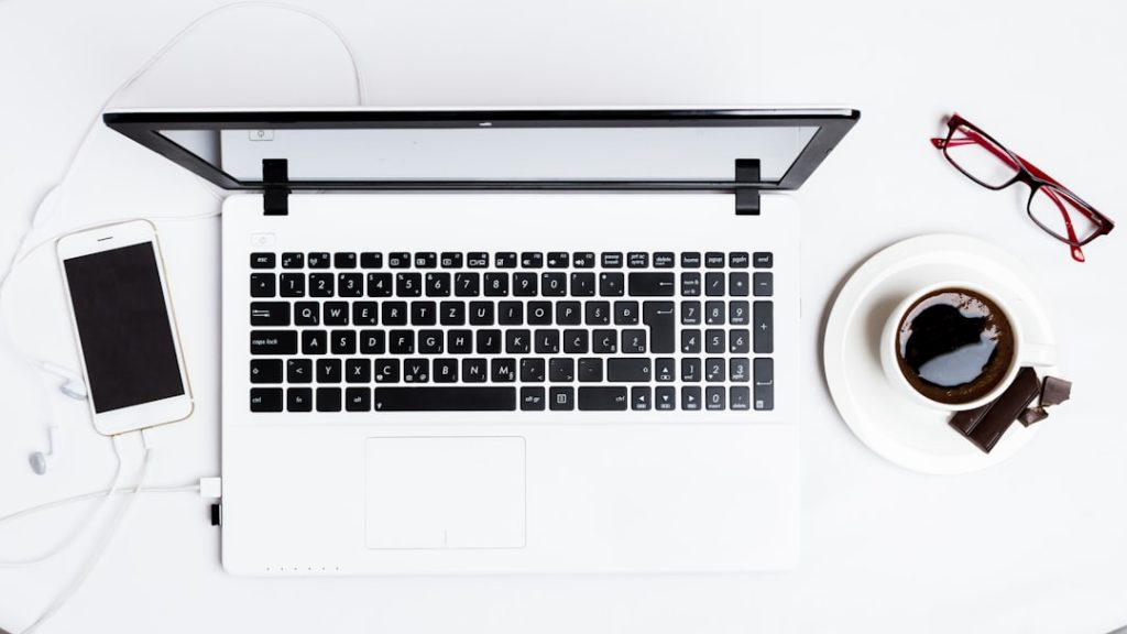 MacBook Pro between smartphone and teacup on white surface plumbing business laptop wordpress theme design - AI Bud