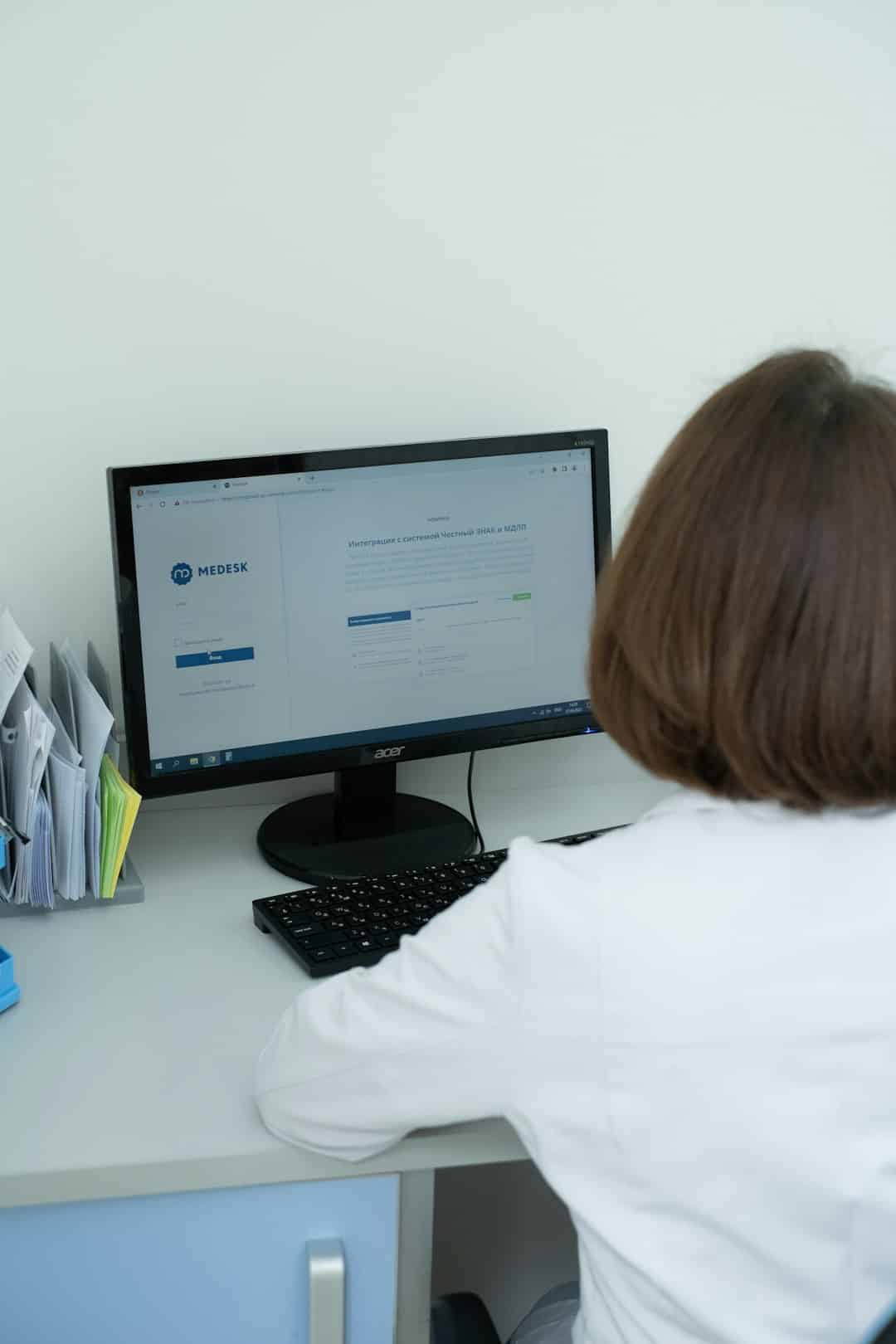a woman sitting at a desk looking at a computer screen healthcare document ai automation - AI Bud