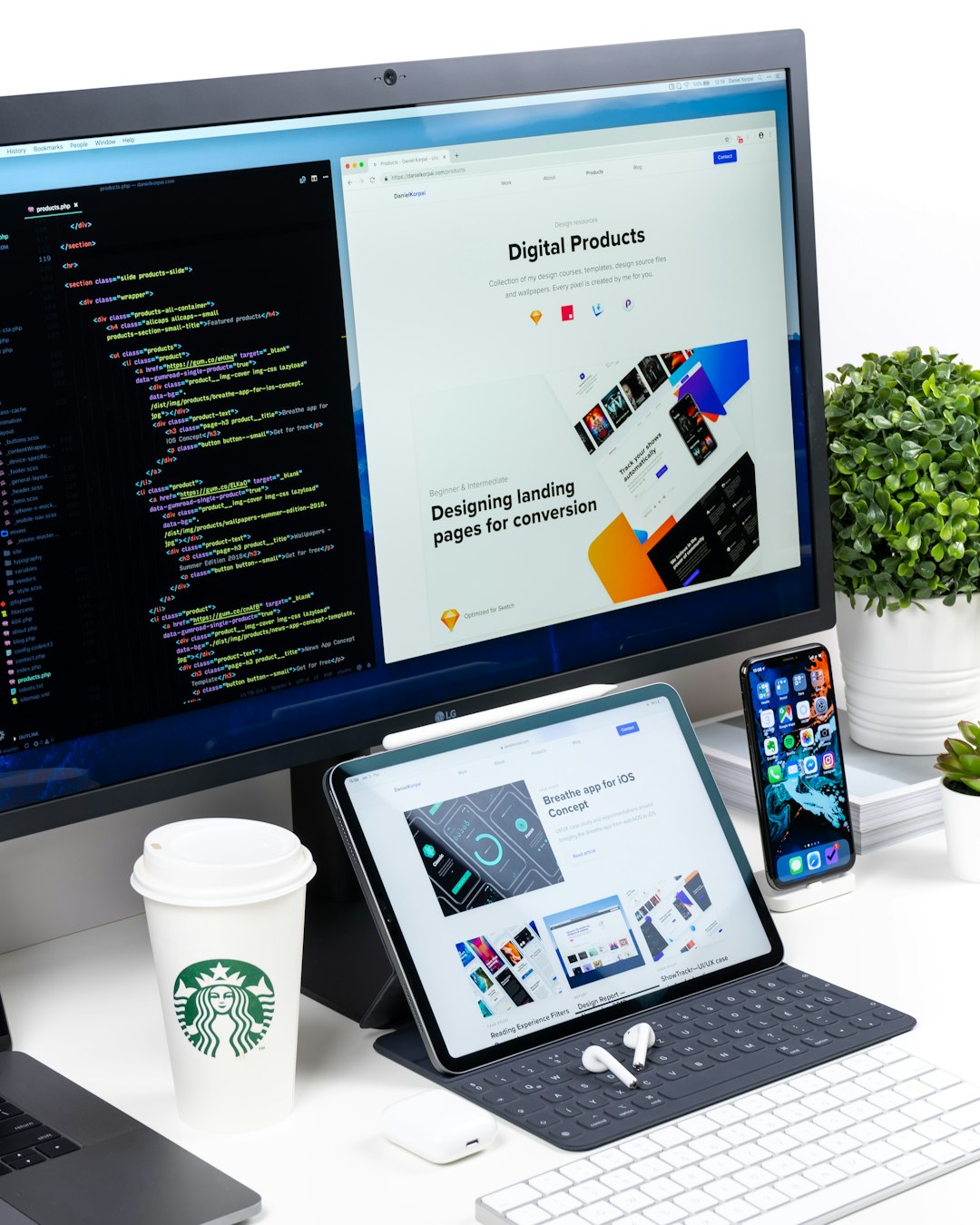 Desktop monitor shows code on the left and a design webpage on the right; tablet, iPhone, coffee cup, and plant on a white desk.