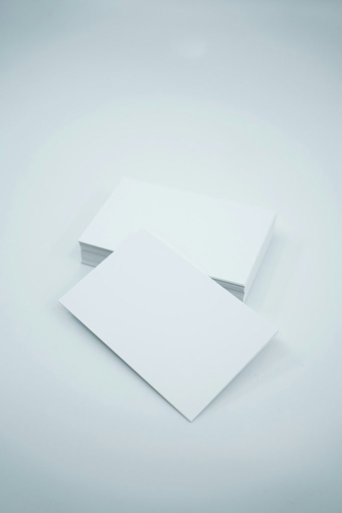Two blank white business cards on a pale blue surface, one resting atop the other at a slight angle.