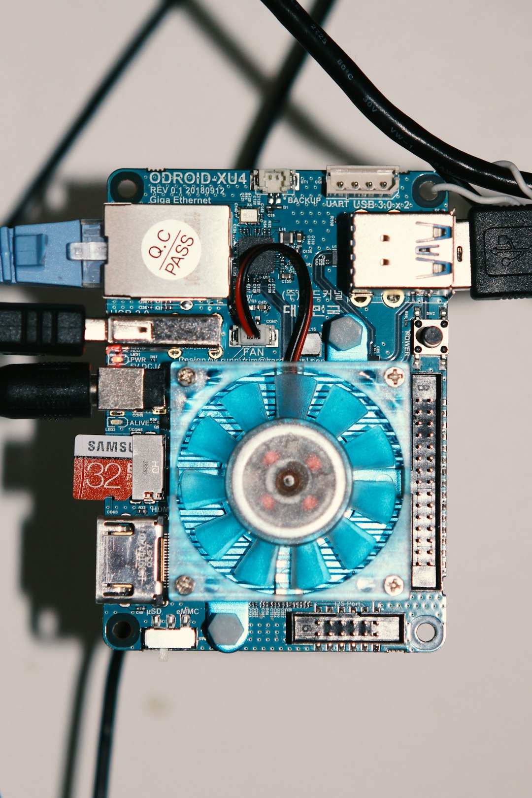 Blue PC motherboard with a central blue cooling fan, USB ports, and Ethernet jack visible.