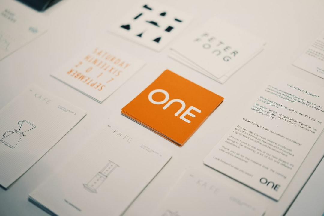 Orange card with the word ONE on it, surrounded by white business cards on a desk.
