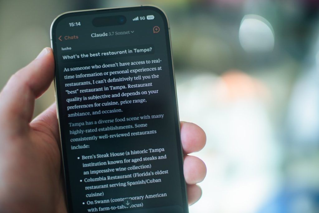 Close-up of a hand holding a smartphone displaying a chat about the best restaurants in Tampa.