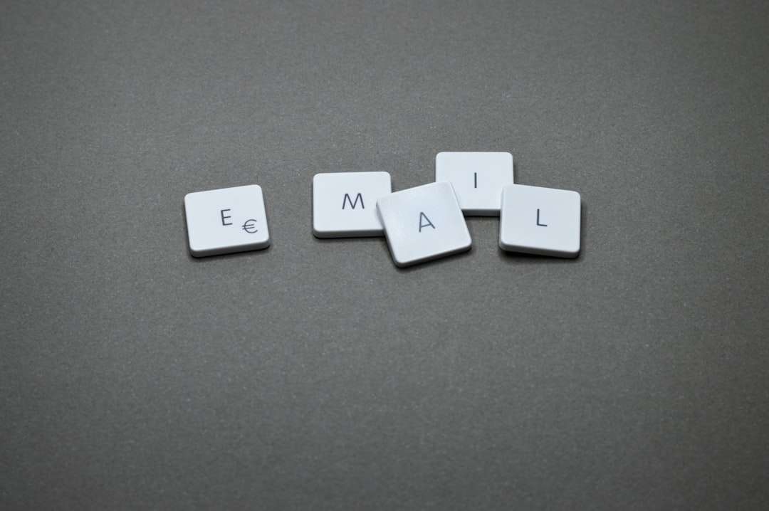 White square tiles with the letters E, M, A, I, L scattered on a gray surface to spell 'EMAIL'.