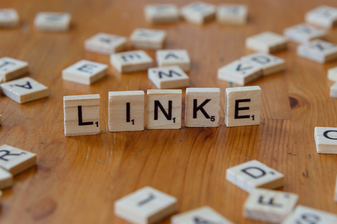 Wooden letter tiles spell 'LINKE' on a brown table, with other tiles scattered around.
