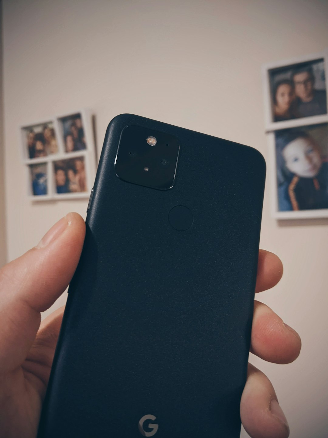 Close-up of a dark blue Google Pixel phone held in a hand, showing the square camera module on the back and the fingerprint sensor nearby.