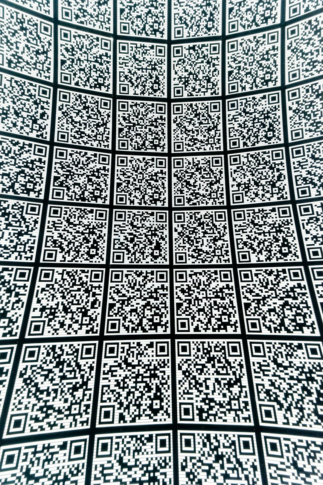 Grid of black-and-white QR codes covering a curved surface.