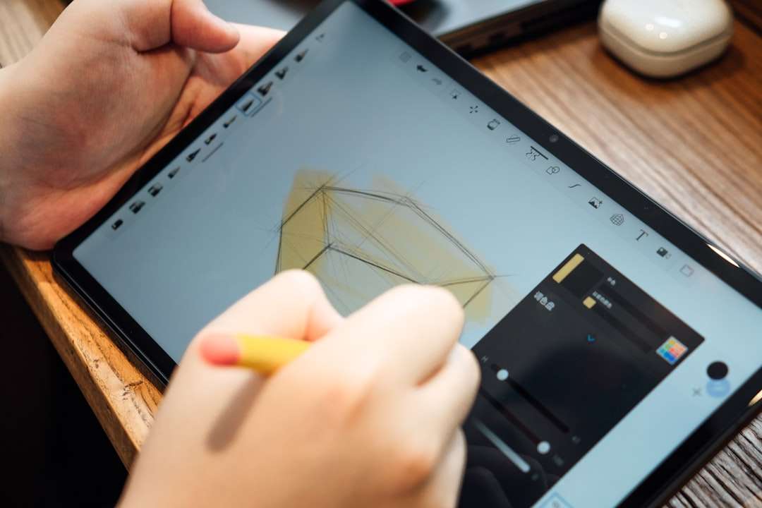 Person drawing a geometric shape on a tablet with a stylus using a drawing app on screen