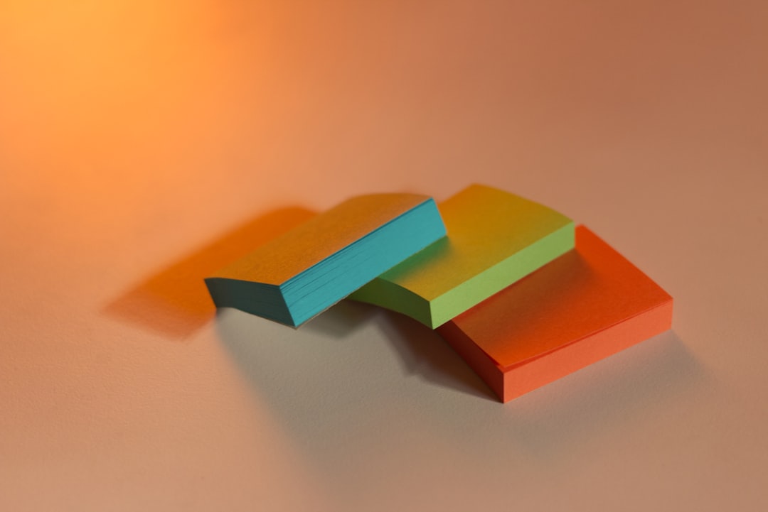 Three small neon-colored rectangular blocks (blue, green, orange) arranged in a loose triangle on a warm gradient surface.