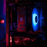 Interior of a desktop gaming PC with a bright blue case fan and red LED lighting highlighting a high-end GPU and motherboard accents
