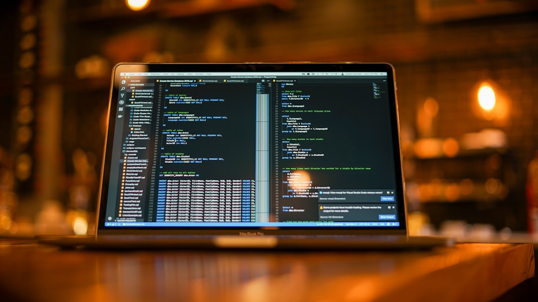 Laptop on a wooden table displaying a split-screen code editor in a cozy cafe setting.