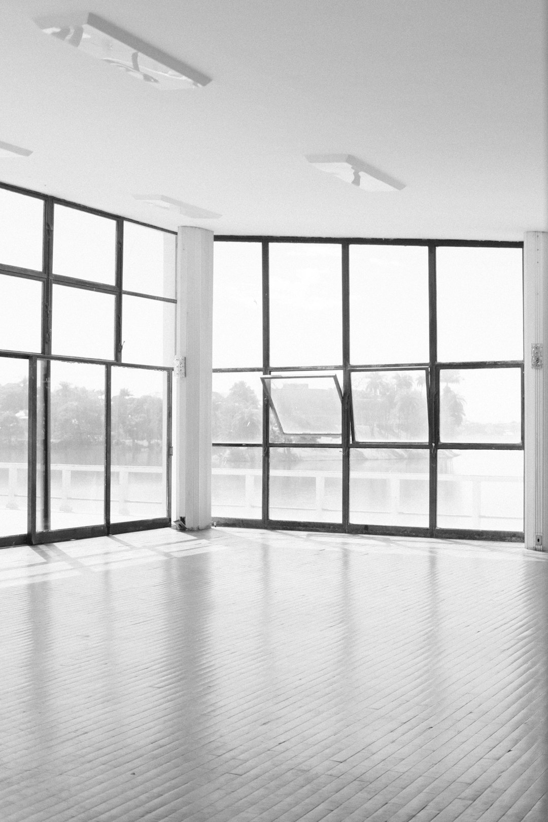Bright, empty studio space with floor-to-ceiling windows and light wooden floor