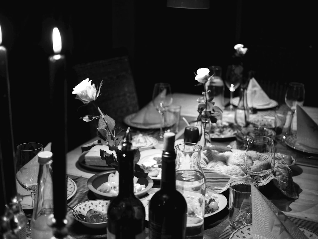 Black-and-white dining table set for dinner with candles, wine bottles, glasses, and roses as centerpieces.