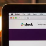 Close-up of a laptop screen showing the Slack homepage in a Safari browser on a macOS window.