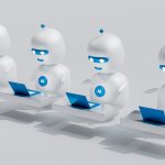 Four white AI robots sitting at desks with blue laptops, lined up and working together.