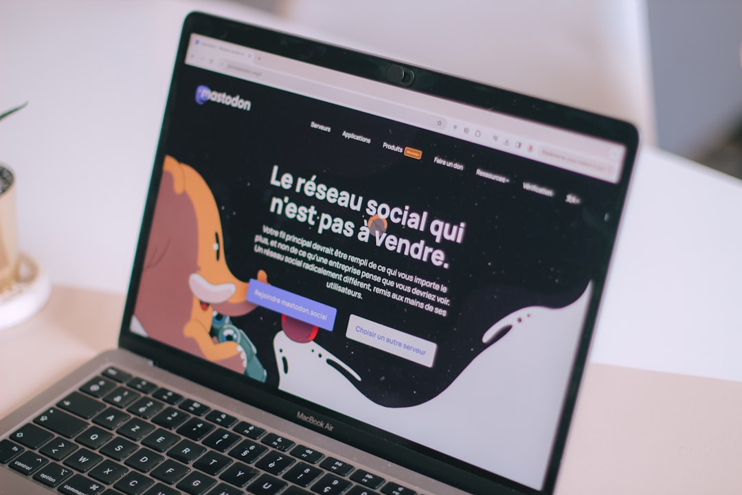 Laptop screen showing Mastodon’s homepage with the French slogan 'Le réseau social qui n’est pas à vendre' and colorful illustrated figures on a dark background.