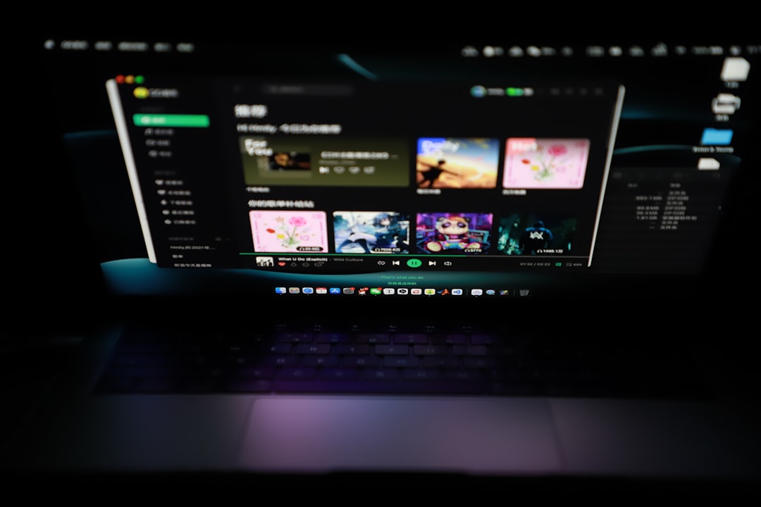Blurred dark laptop screen showing a streaming app with colorful thumbnails and a green playback bar on the bottom edge.