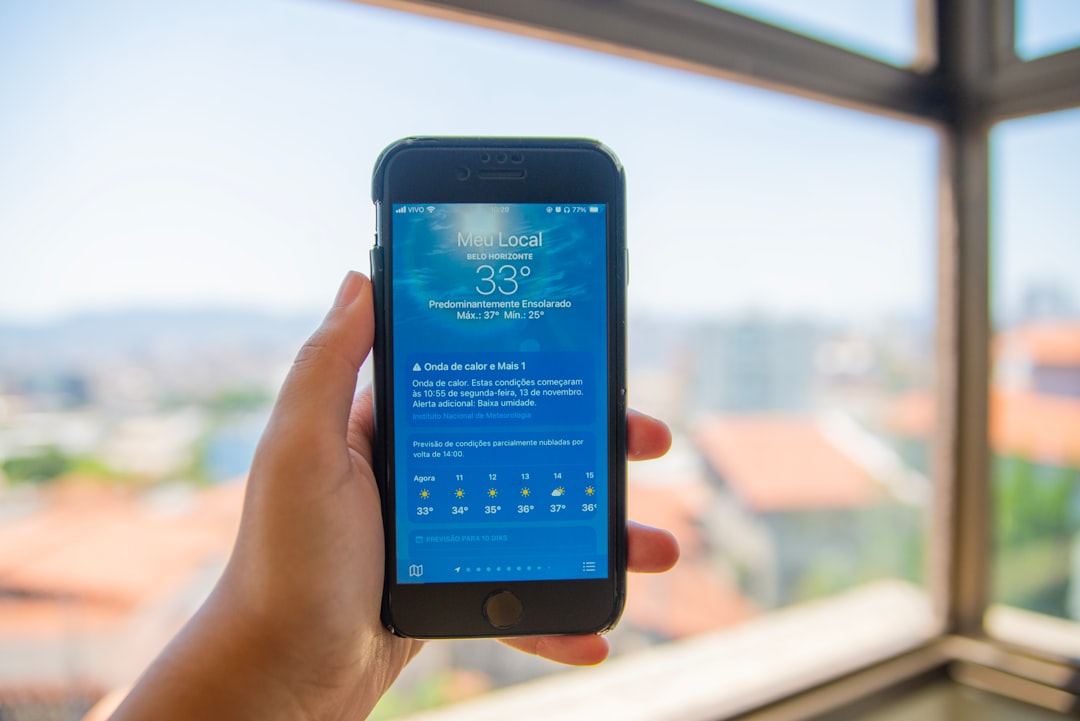 a person holding a cell phone in front of a window online booking confirmation screen appointment reminder notification mobile scheduling app - AI Bud