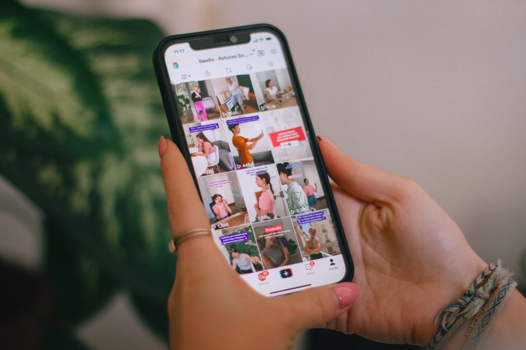 Person holding a smartphone displaying a grid of video thumbnails on screen.