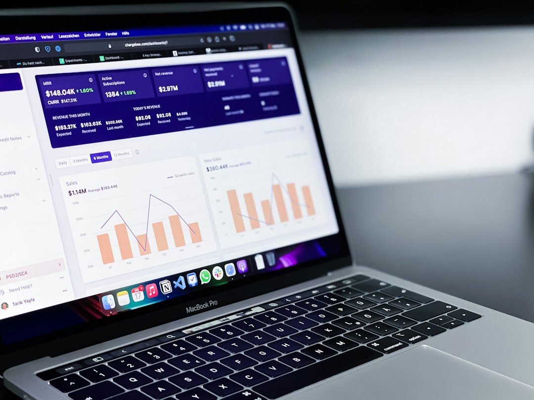 MacBook Pro screen showing a business analytics dashboard with bar and line charts and revenue metrics in purple UI