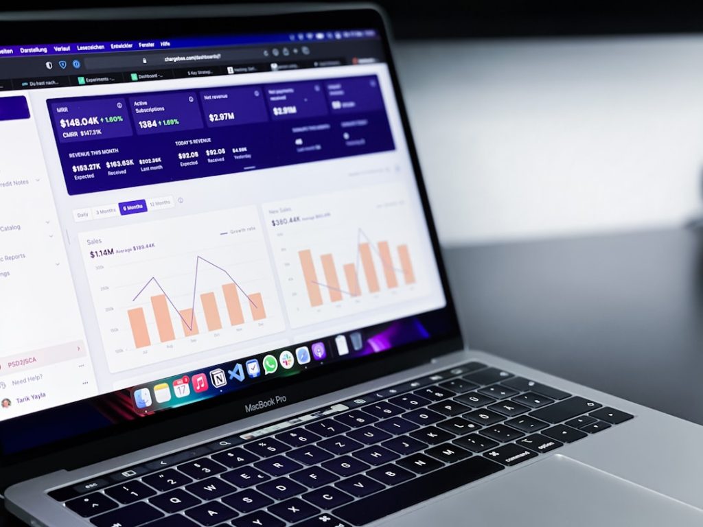 MacBook Pro displaying a financial dashboard with bar and line charts and revenue metrics on screen.
