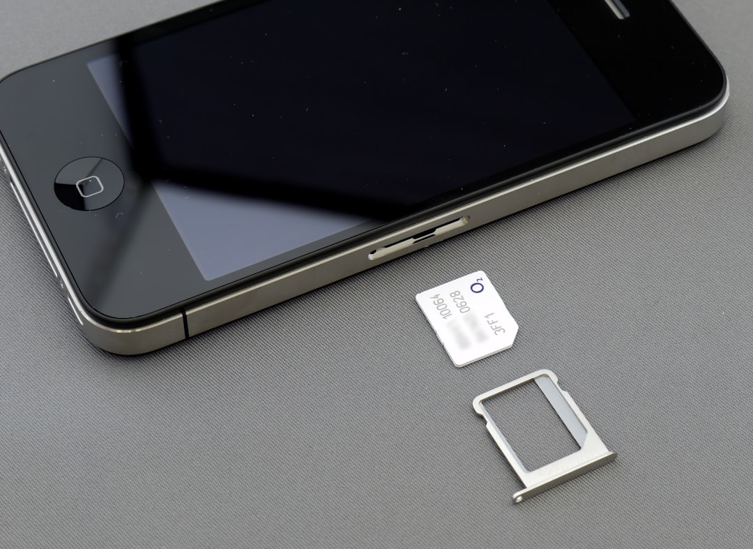 Close-up of a smartphone with the SIM card tray ejected and a SIM card next to it on a gray surface.