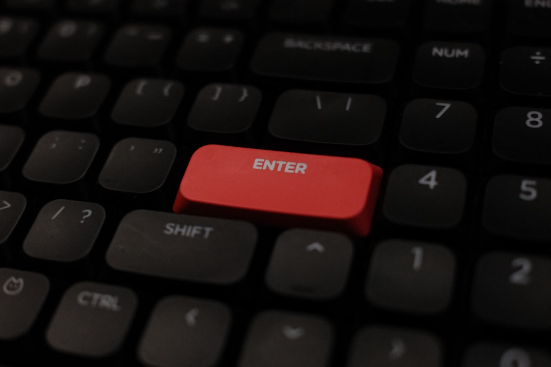 Close-up of a bright red Enter key on a dark computer keyboard, standing out among the surrounding grey keys.