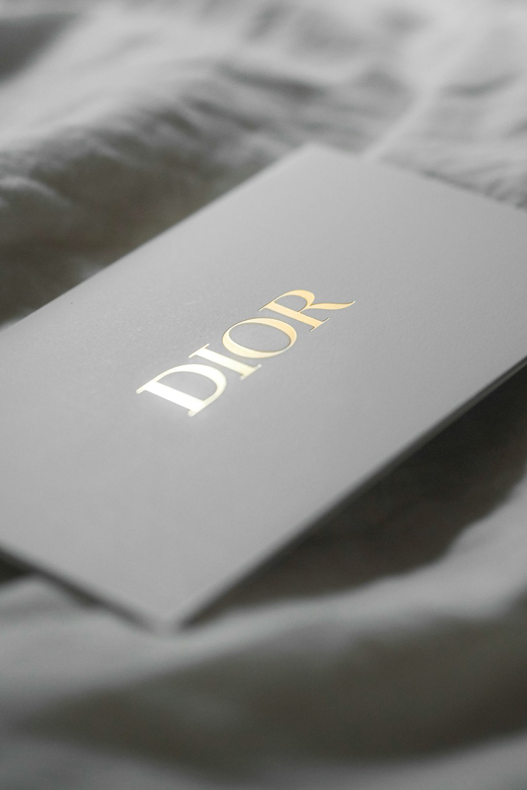 Grey Dior box with gold DIOR logo resting on soft fabric surface.