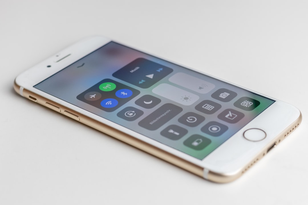 Gold iPhone lying on its side showing the Control Center with music controls and toggles (Wi‑Fi, Bluetooth, brightness).