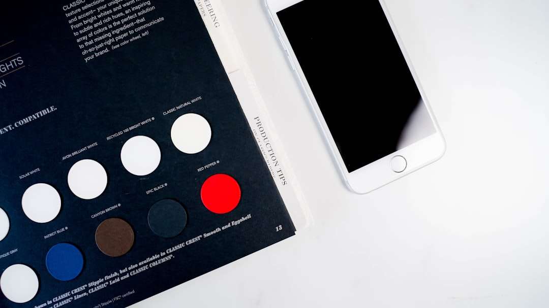 Color swatch catalog open on a desk with circular color chips beside a white smartphone.