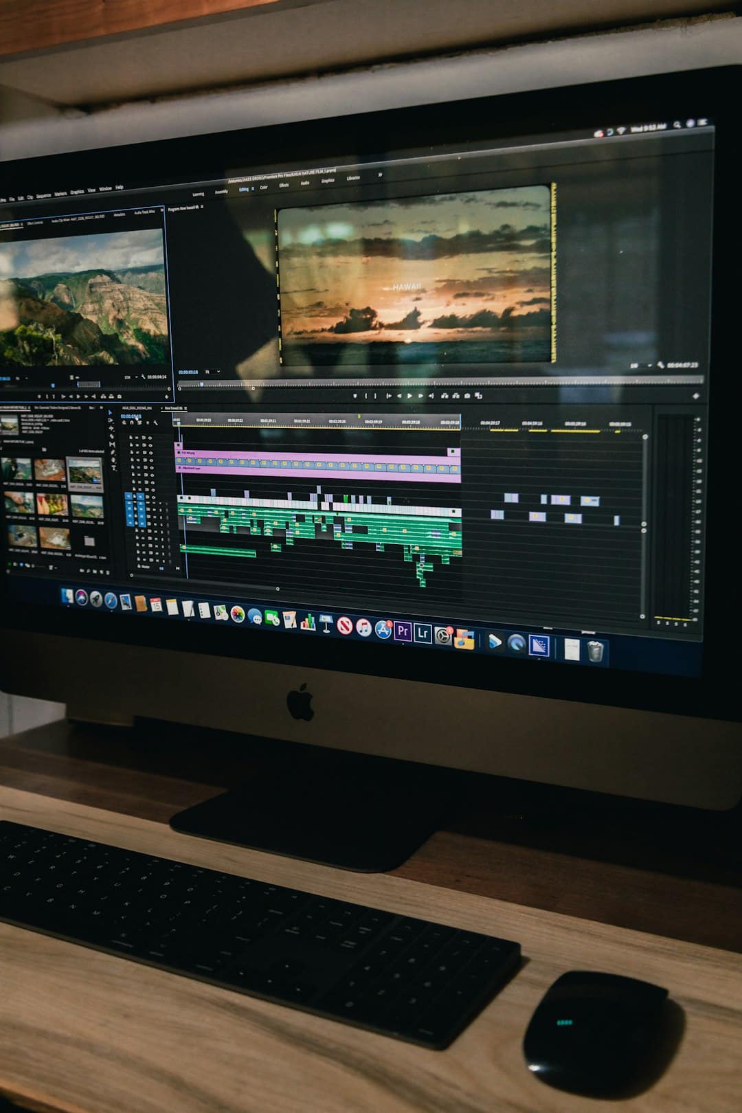 iMac screen with a video editing timeline and a sunset frame in the preview window, multiple track layers visible.