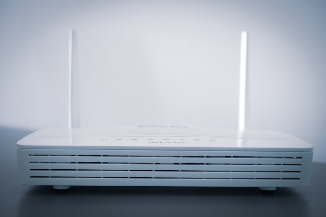 White wireless router with two vertical antennas on a dark tabletop, front vents visible.
